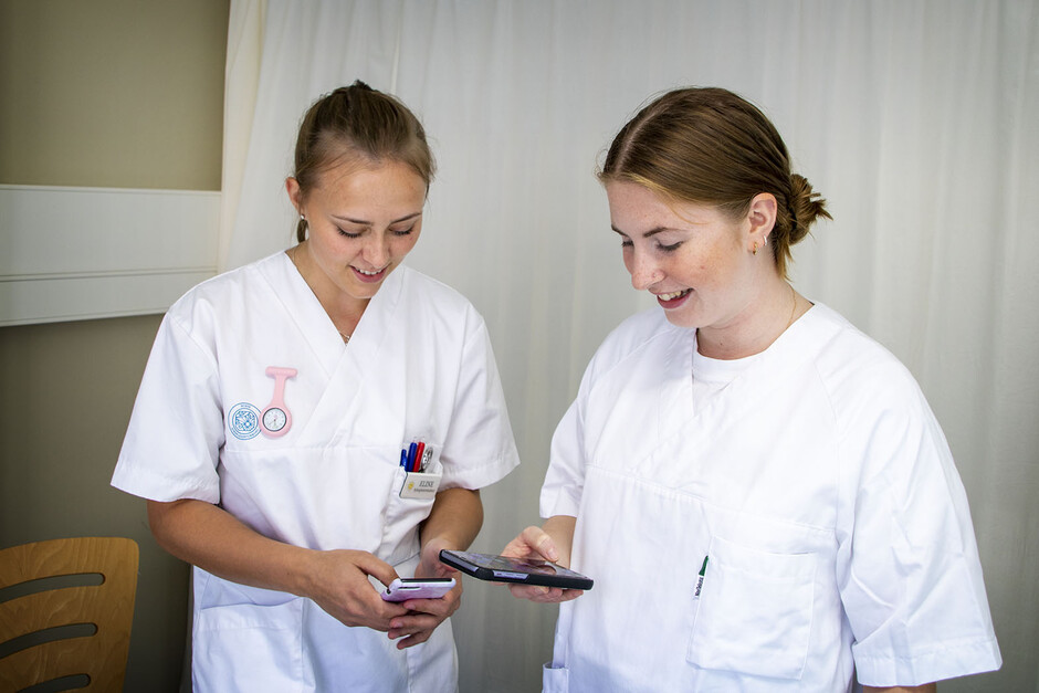 Two nurse checking their mobiles.
